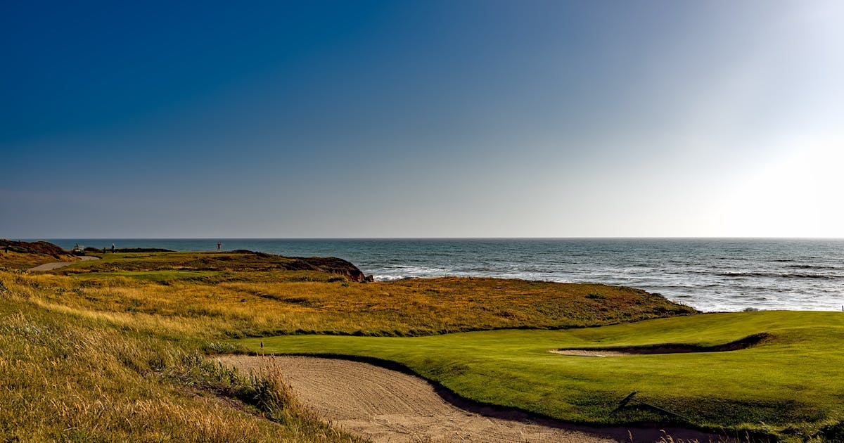 Coastal golf course along the Scottish shoreline under a clear blue sky