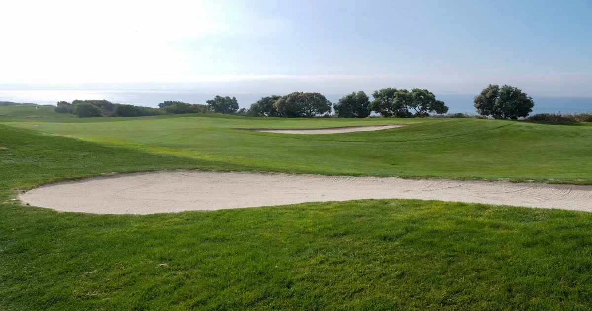 An aerial view of a beautifully manicured golf course with bunkers and greens