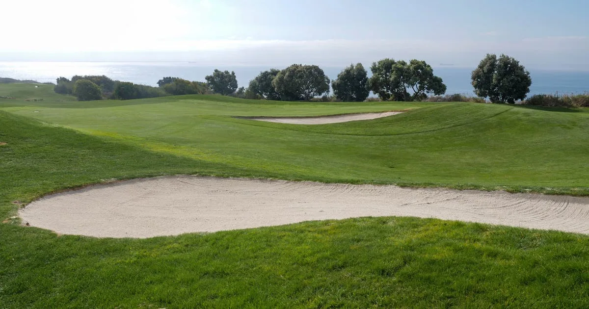 Golf course with sand trap and ocean view under a clear blue sky