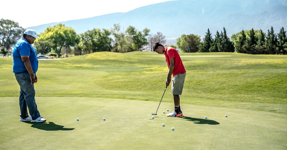 Golfers putting on a Welsh golf course with mountain views in the background