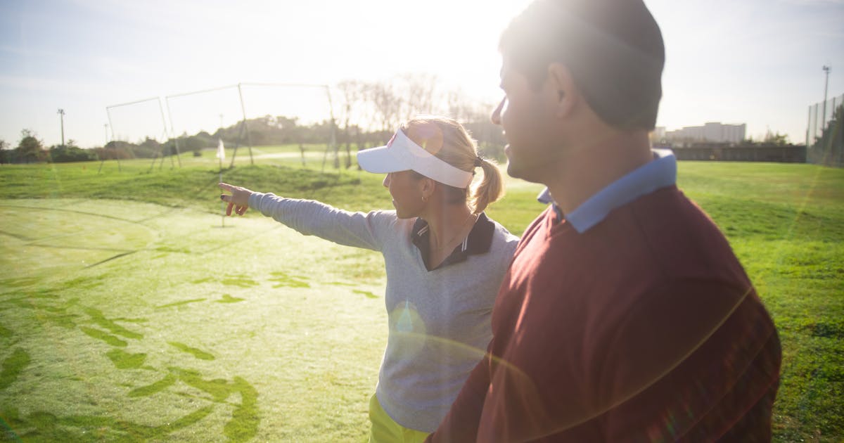 Two golfers chatting on a golf course on a sunny day