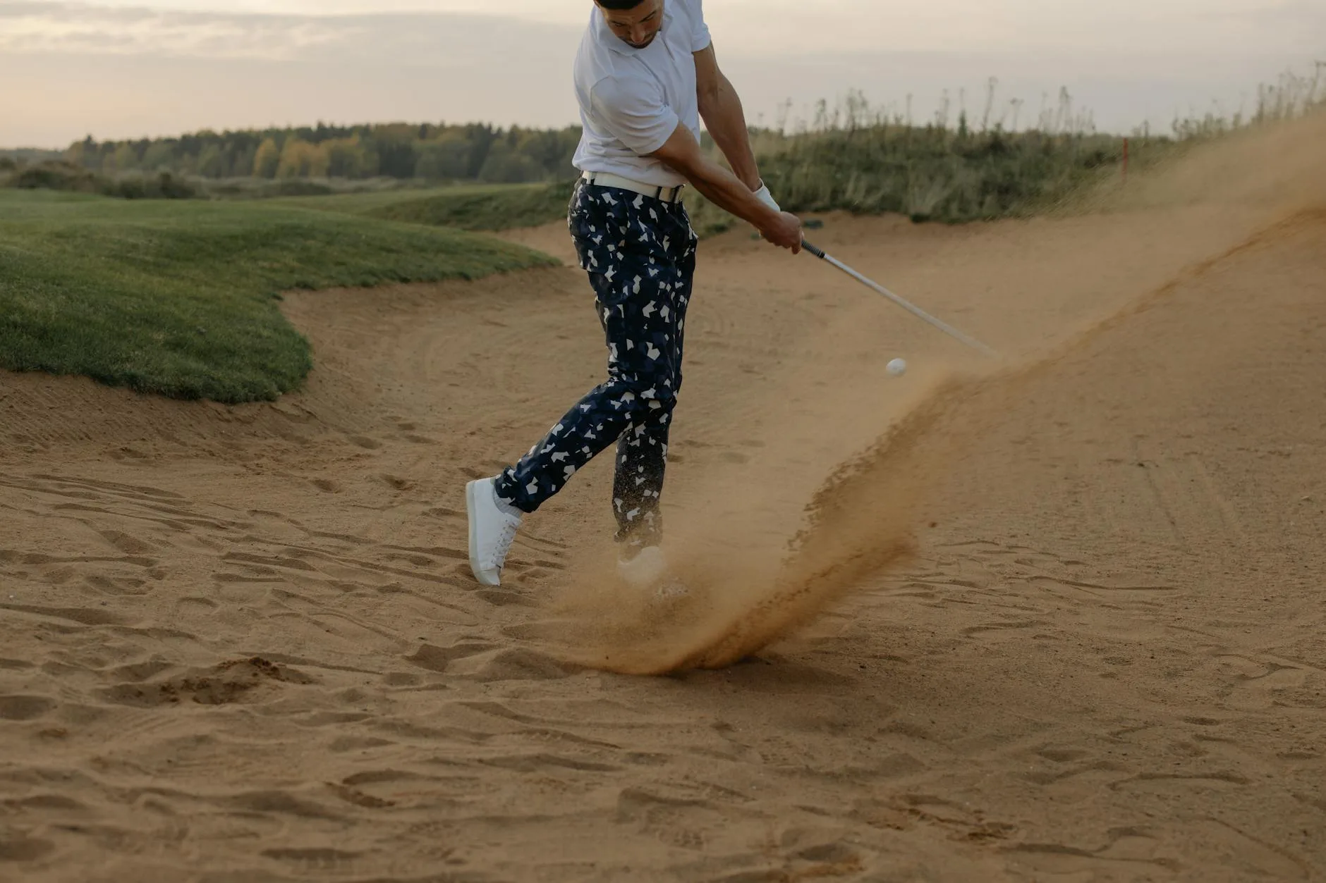 A golfer hitting an iron shot from the fairway on a sunny day